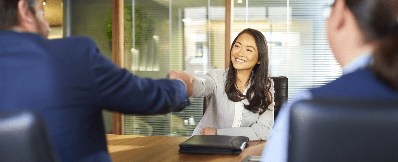 Female and male professionals shaking hands over table