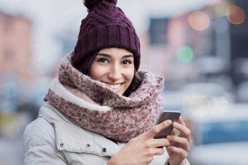 Female student holding cell phone outdoor in winter